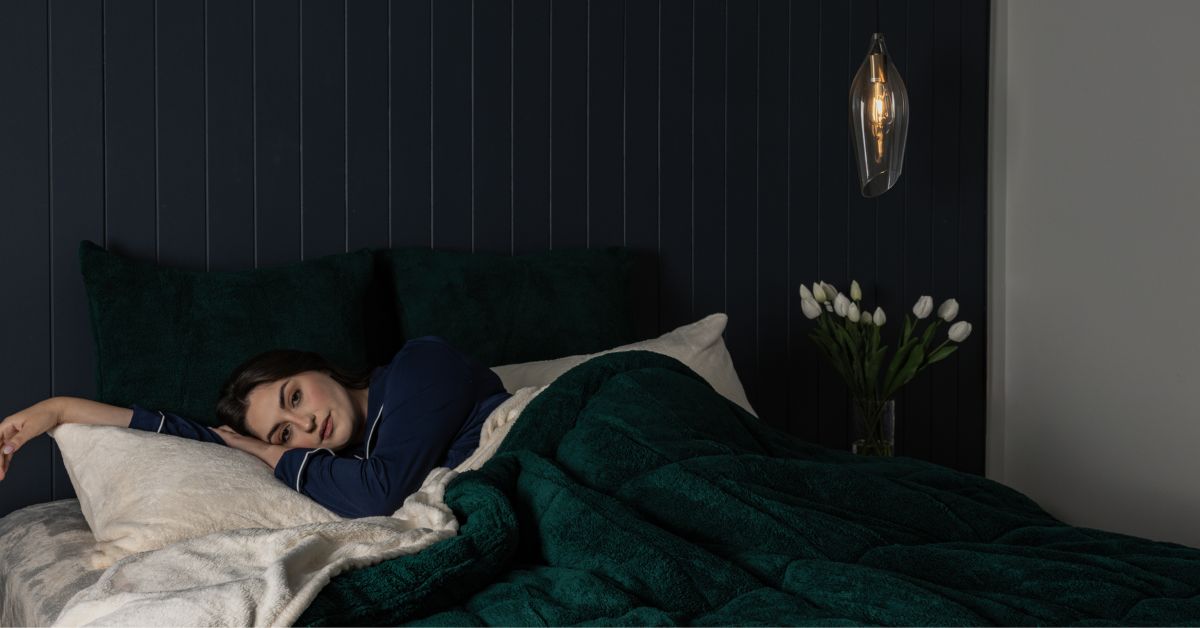 Women lying in a green fluffy snuggle fleece comforter in bed